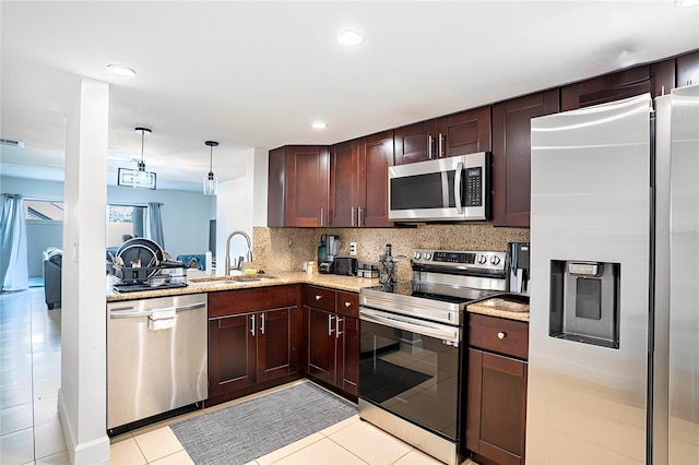 kitchen with tasteful backsplash, appliances with stainless steel finishes, sink, pendant lighting, and light tile patterned floors