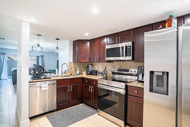 kitchen with tasteful backsplash, hanging light fixtures, light tile patterned floors, sink, and stainless steel appliances