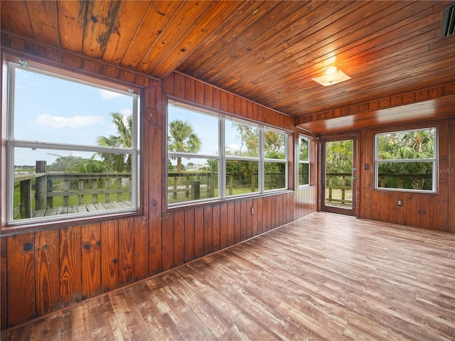 unfurnished sunroom featuring a water view, a healthy amount of sunlight, and wooden ceiling