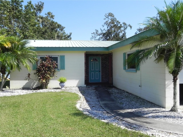 view of exterior entry featuring a yard, concrete block siding, and metal roof