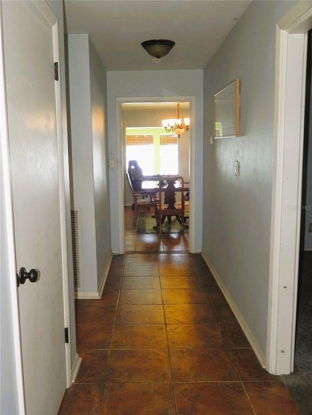 hall with a chandelier, tile patterned flooring, and baseboards