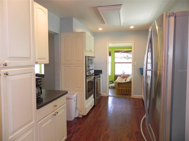 kitchen with dark wood-style flooring, appliances with stainless steel finishes, dark countertops, recessed lighting, and white cabinetry