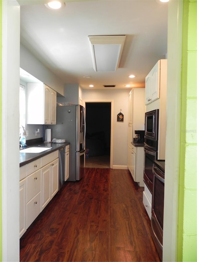 kitchen featuring dark countertops, dark wood-type flooring, built in microwave, oven, and a sink