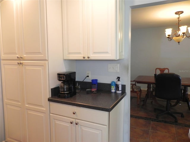 kitchen featuring white cabinetry, decorative light fixtures, dark tile patterned flooring, and a notable chandelier