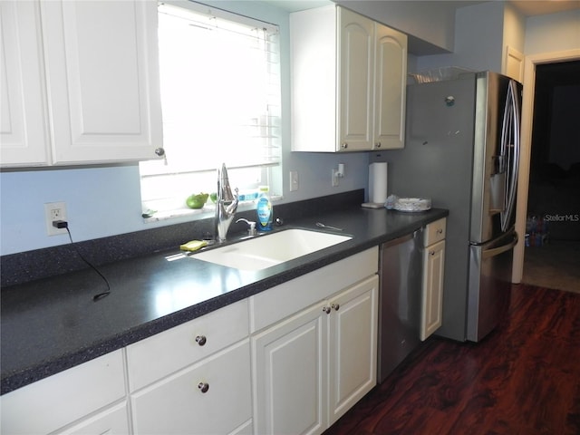 kitchen with dark countertops, dark wood-type flooring, a healthy amount of sunlight, stainless steel appliances, and a sink