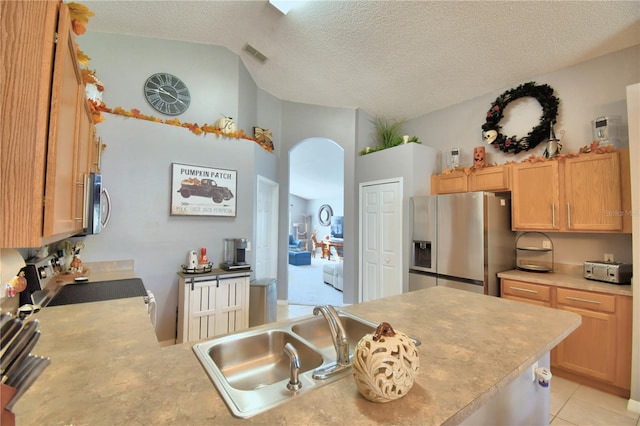 kitchen featuring light tile patterned flooring, a textured ceiling, stainless steel appliances, and sink