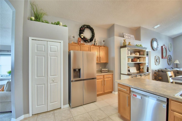 kitchen featuring light brown cabinetry, appliances with stainless steel finishes, a textured ceiling, and light tile patterned floors