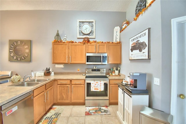 kitchen with light tile patterned flooring, a textured ceiling, stainless steel appliances, and sink