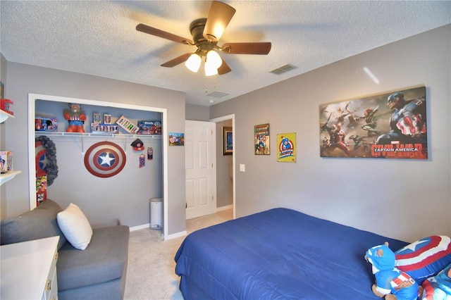 bedroom with a closet, ceiling fan, a textured ceiling, and light colored carpet