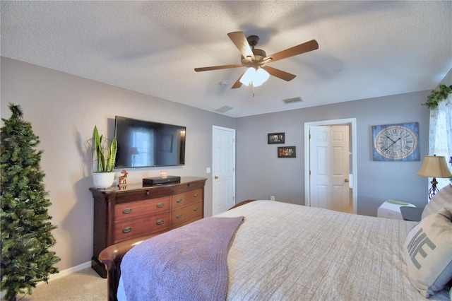 carpeted bedroom featuring a textured ceiling and ceiling fan