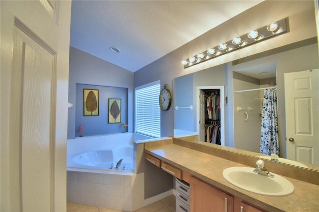 bathroom featuring a relaxing tiled tub, a textured ceiling, tile patterned floors, lofted ceiling, and vanity