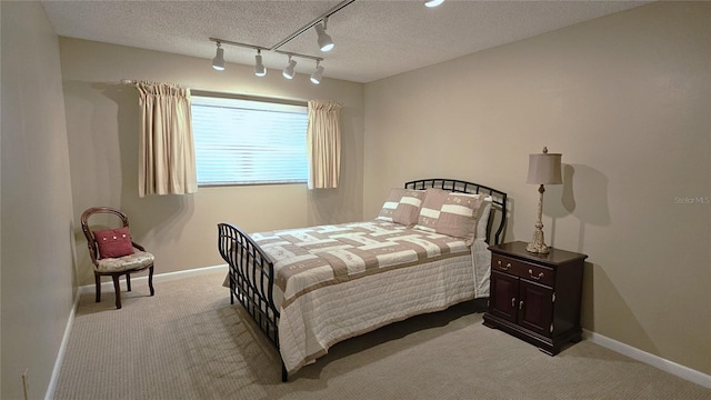 bedroom with light carpet, track lighting, and a textured ceiling