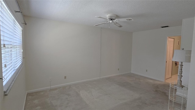 carpeted empty room featuring ceiling fan and a textured ceiling