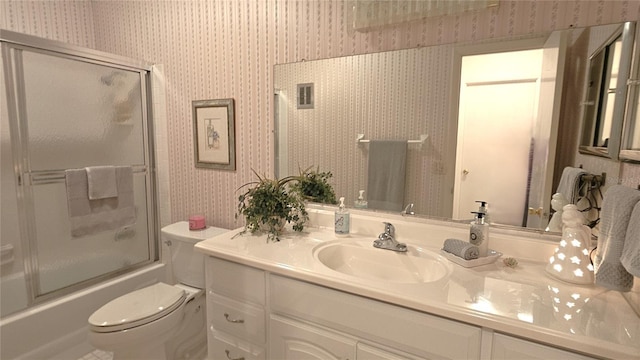 full bathroom featuring vanity, toilet, and shower / bath combination with glass door