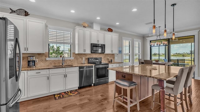 kitchen with white cabinets, appliances with stainless steel finishes, a healthy amount of sunlight, and a center island