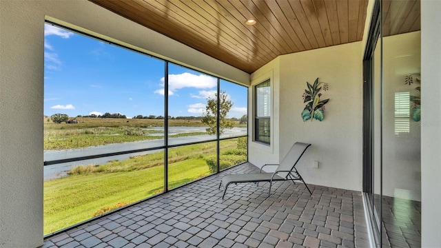 unfurnished sunroom with wood ceiling and a water view