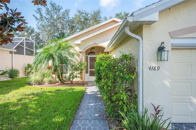 entrance to property with a garage, stucco siding, and a lawn