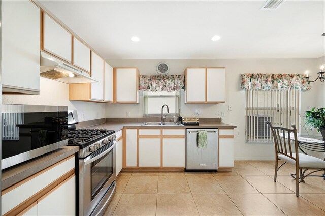 kitchen featuring an inviting chandelier, sink, stainless steel appliances, white cabinets, and light tile patterned floors