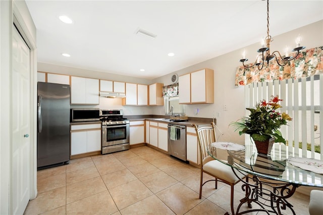 kitchen with stainless steel appliances, decorative light fixtures, a notable chandelier, and light tile patterned floors