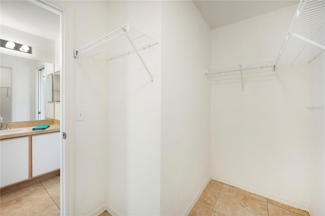 spacious closet with light tile patterned floors and sink