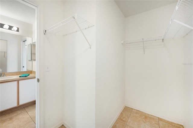 walk in closet with light tile patterned floors and a sink