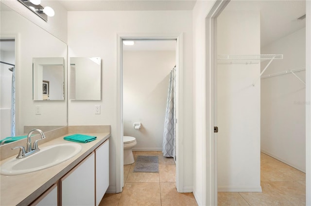 bathroom with vanity, a spacious closet, visible vents, toilet, and tile patterned floors