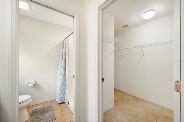 full bath featuring toilet, curtained shower, a spacious closet, and visible vents