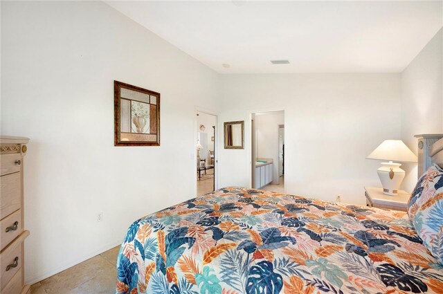 tiled bedroom featuring lofted ceiling and connected bathroom