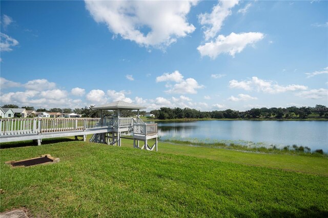 dock area with a gazebo, a water view, and a yard