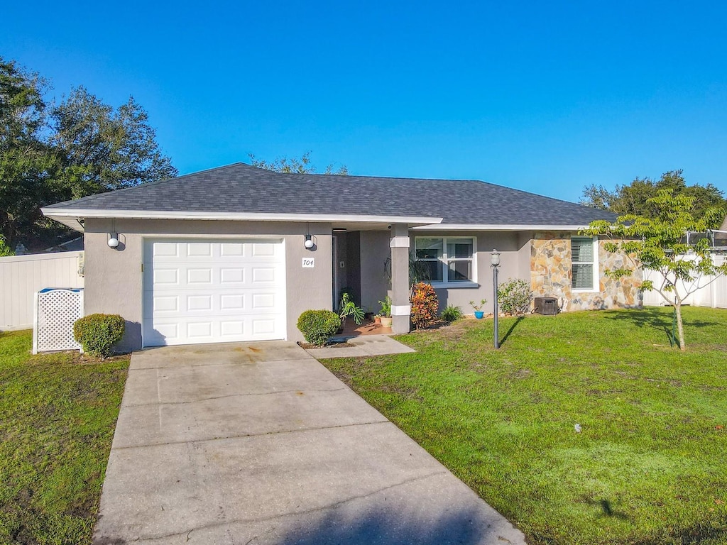 ranch-style home featuring a front yard, cooling unit, and a garage