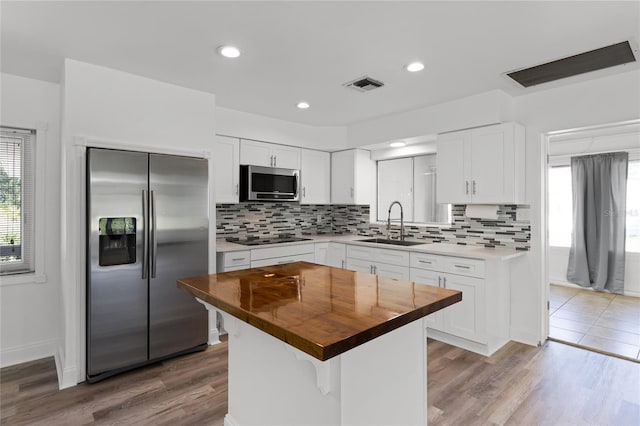 kitchen featuring sink, a kitchen island, butcher block counters, stainless steel appliances, and hardwood / wood-style flooring