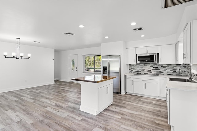 kitchen with stainless steel appliances, sink, a center island, white cabinets, and light hardwood / wood-style floors