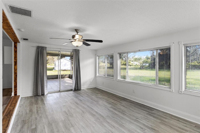 spare room with a textured ceiling, light wood-type flooring, and ceiling fan