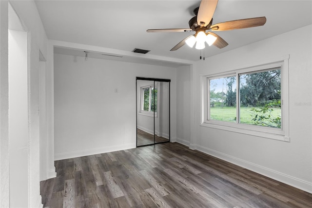 empty room featuring dark hardwood / wood-style floors, a healthy amount of sunlight, and ceiling fan