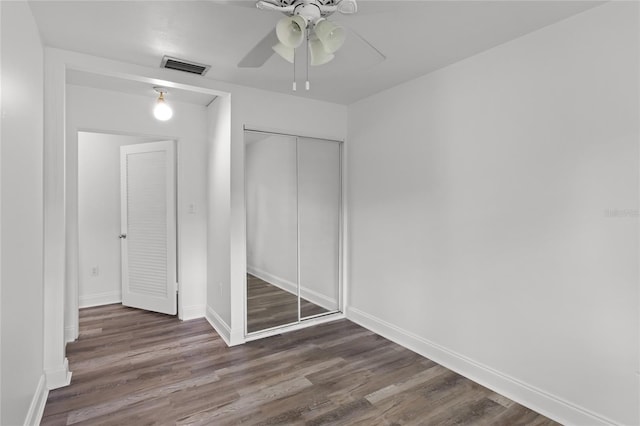 unfurnished bedroom featuring dark hardwood / wood-style flooring, a closet, and ceiling fan