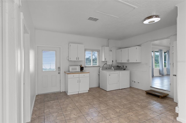 kitchen with white cabinets, washer and dryer, and a healthy amount of sunlight