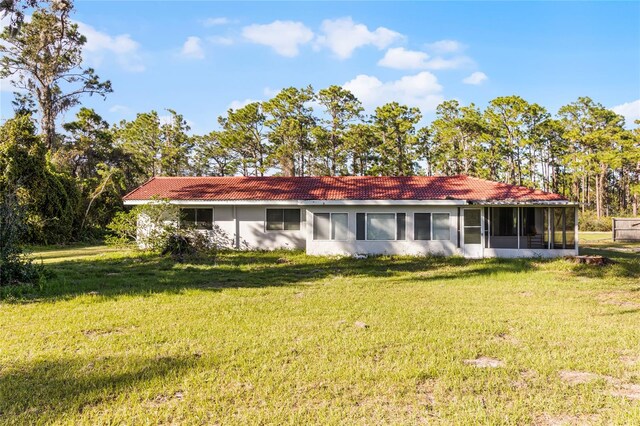 back of property with a yard and a sunroom