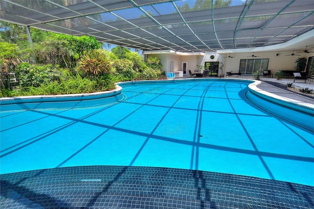 view of swimming pool featuring a patio area, glass enclosure, and ceiling fan