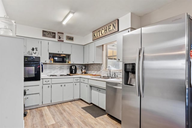 kitchen featuring decorative backsplash, sink, light hardwood / wood-style floors, and black appliances