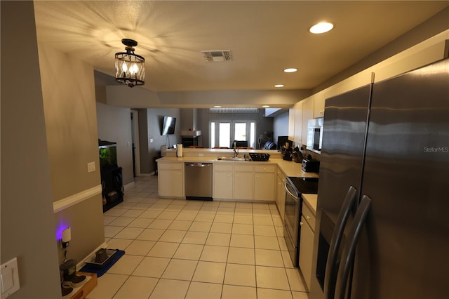 kitchen with kitchen peninsula, white cabinetry, stainless steel appliances, pendant lighting, and an inviting chandelier