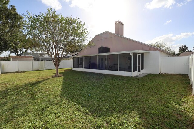 rear view of property with a sunroom and a lawn