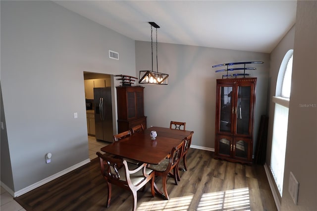 dining room featuring hardwood / wood-style flooring, lofted ceiling, and an inviting chandelier