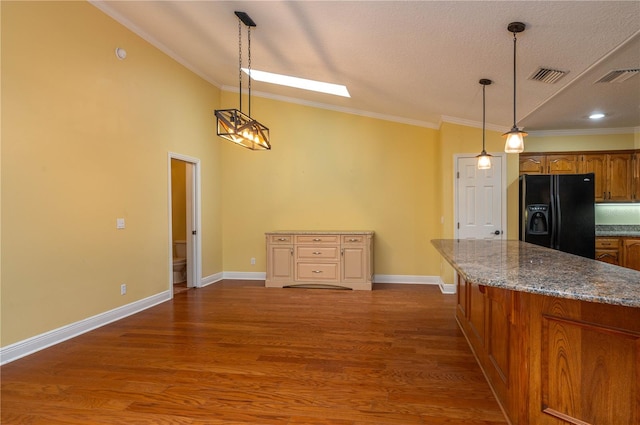 kitchen with dark hardwood / wood-style floors, ornamental molding, black fridge, and hanging light fixtures