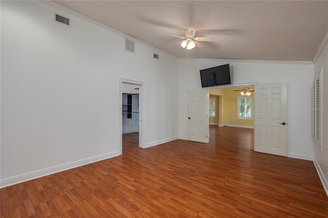 empty room with lofted ceiling, hardwood / wood-style flooring, crown molding, a textured ceiling, and ceiling fan