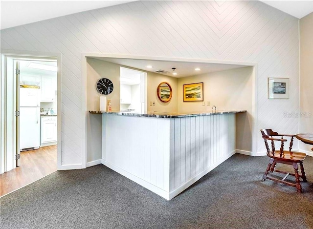 kitchen featuring kitchen peninsula, carpet, vaulted ceiling, and white refrigerator