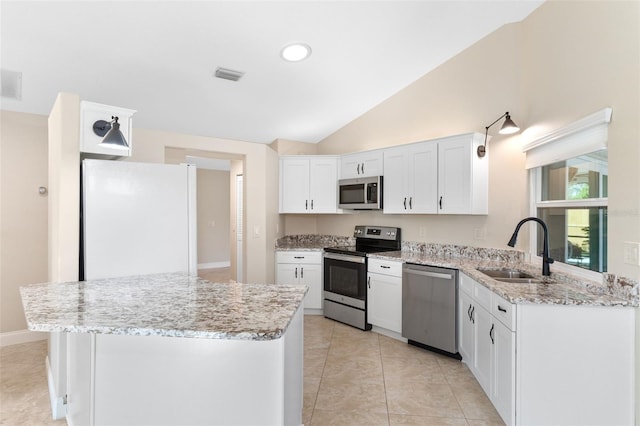 kitchen with sink, white cabinetry, stainless steel appliances, vaulted ceiling, and light stone counters