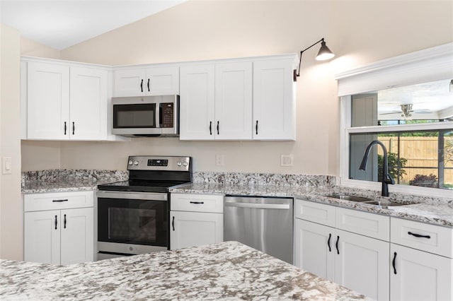 kitchen with white cabinetry, stainless steel appliances, and vaulted ceiling