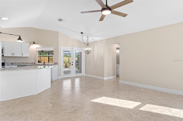 unfurnished living room with lofted ceiling, french doors, light tile patterned flooring, and ceiling fan with notable chandelier