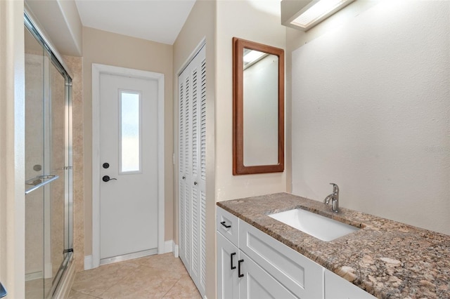 bathroom featuring vanity, a shower with shower door, and tile patterned flooring