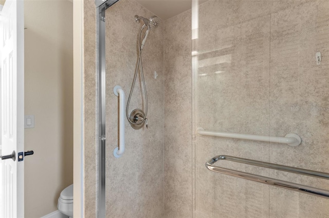 bathroom featuring a shower with door and toilet